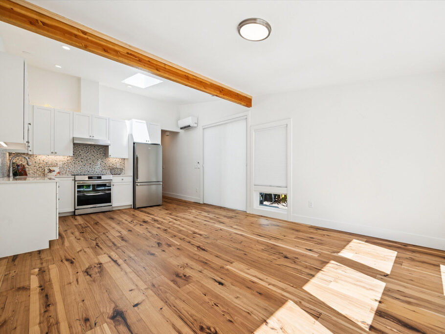 Kitchen and great room in contemporary attached ADU with large windows and hardwood floors.