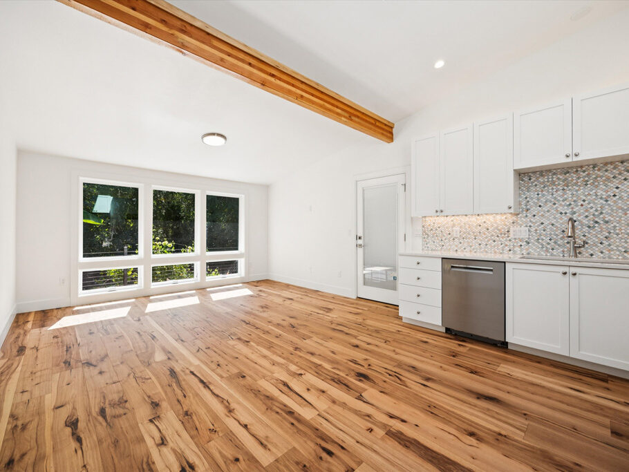 Kitchen and great room in contemporary attached ADU with large windows and hardwood floors.