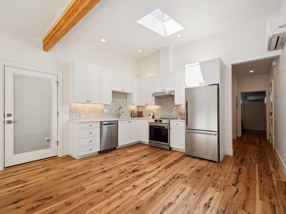 Kitchen and great room in contemporary attached ADU with large windows and hardwood floors.