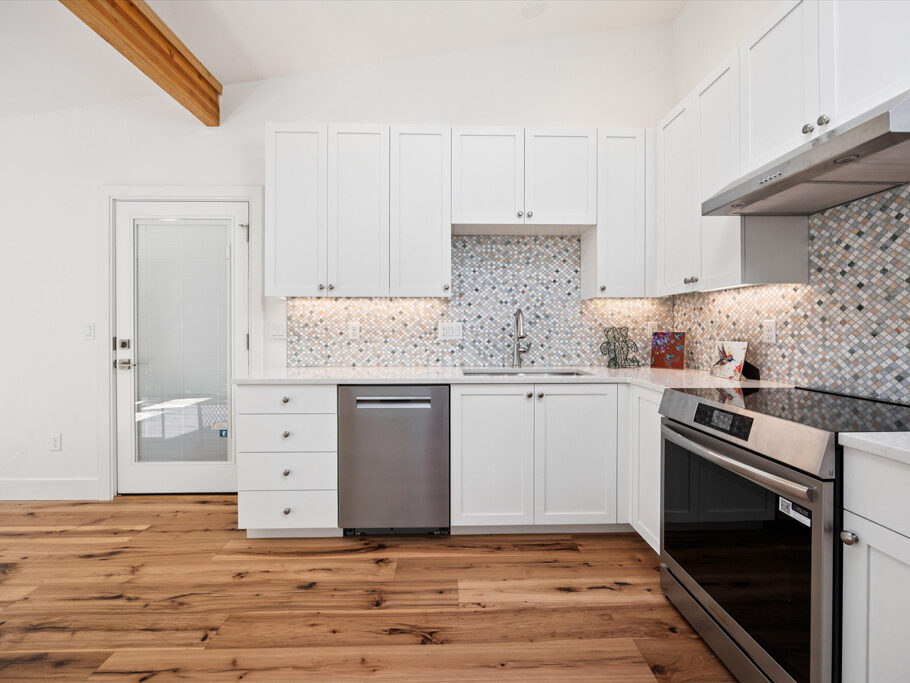 Kitchen and great room in contemporary attached ADU with large windows and hardwood floors.