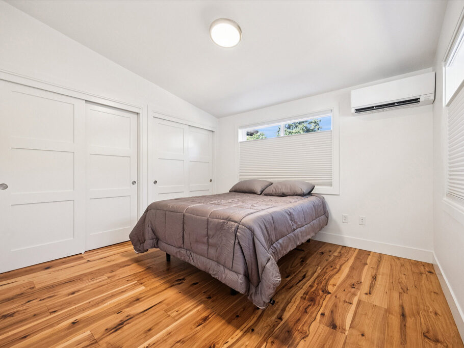 Bedroom in contemporary attached ADU with large windows and hardwood floors.