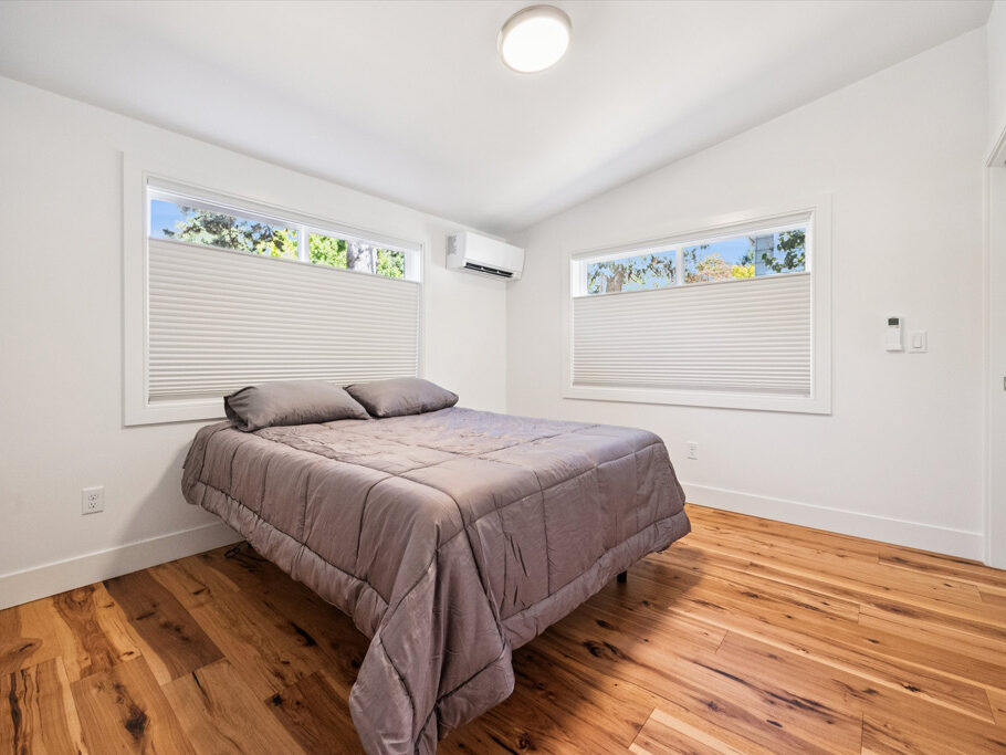 Bedroom in contemporary attached ADU with large windows and hardwood floors.