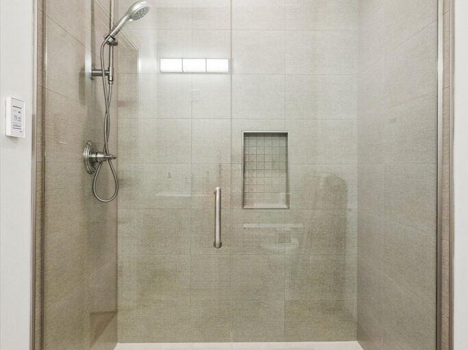 Shower in contemporary attached ADU with large windows and hardwood floors.