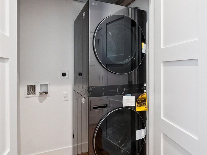 Full laundry in contemporary attached ADU with large windows and hardwood floors.